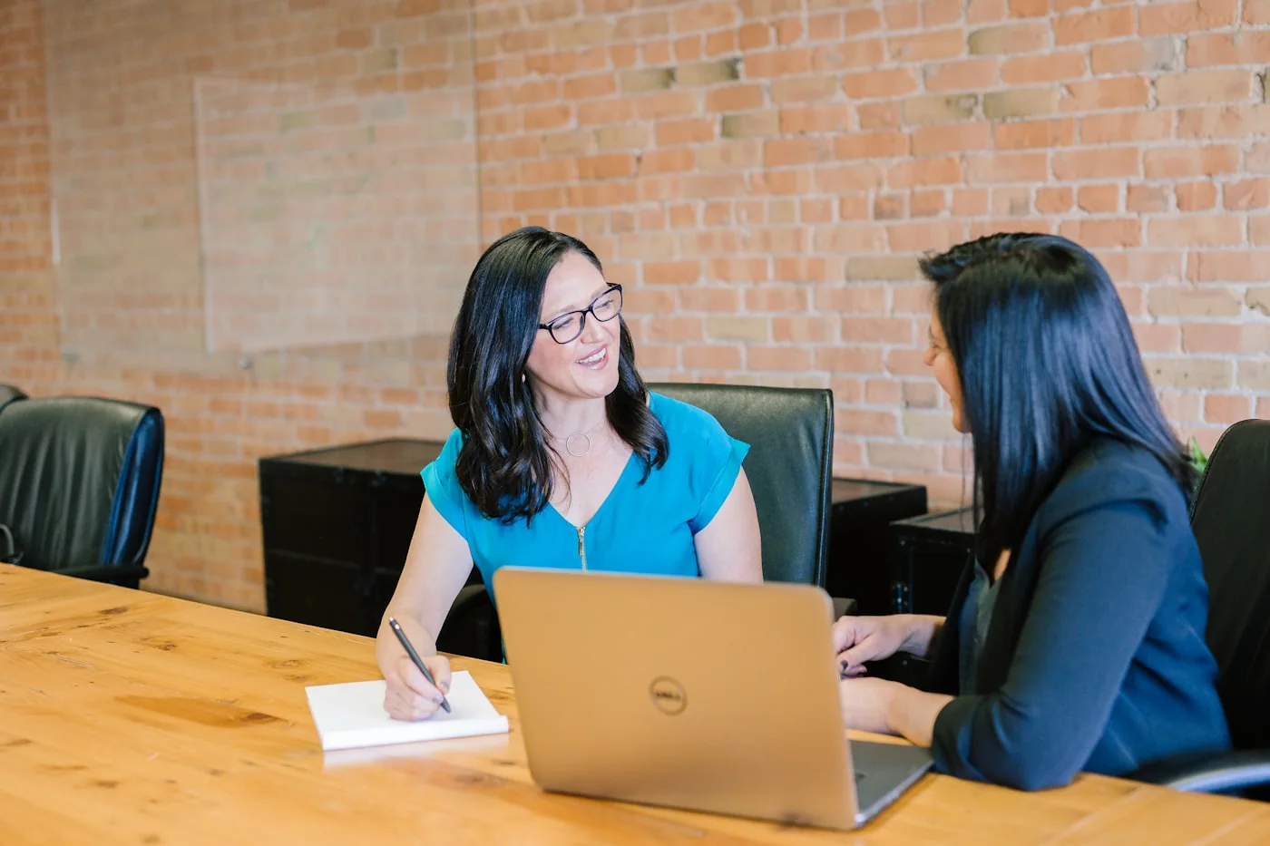 Two colleagues discussing material beside a laptop and notebook